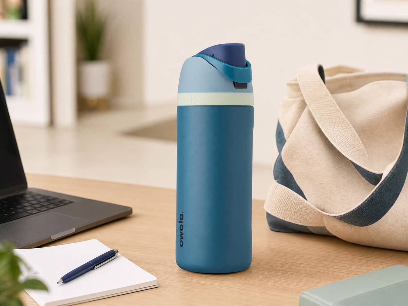 Blue Owala FreeSip bottle beside a laptop