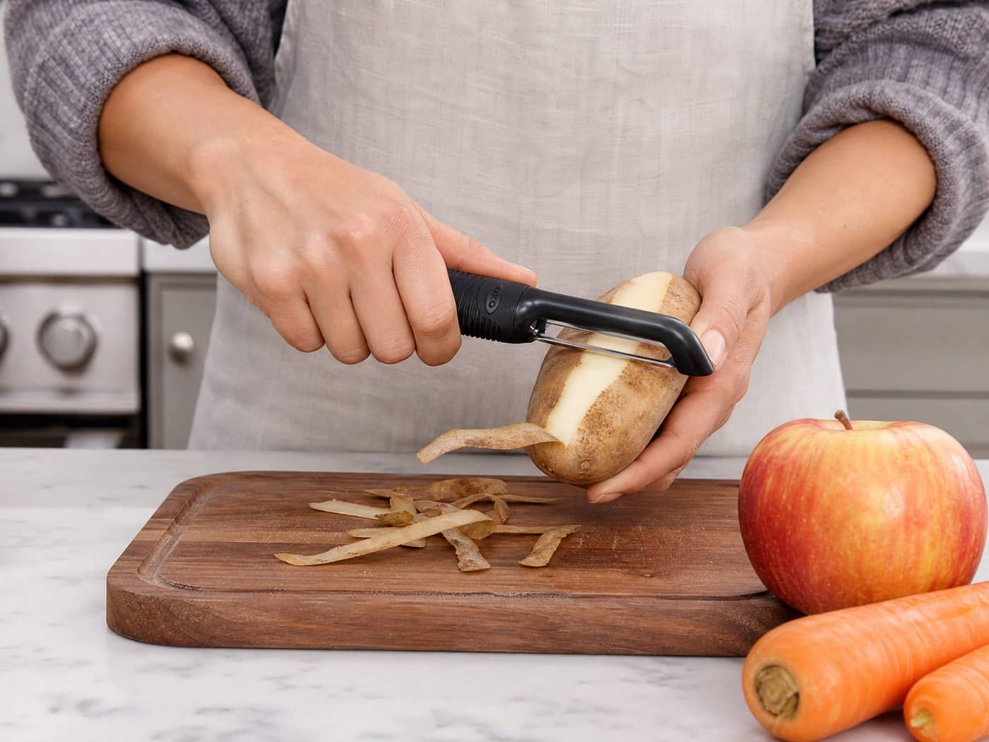 Person using OXO swivel peeler on a potato